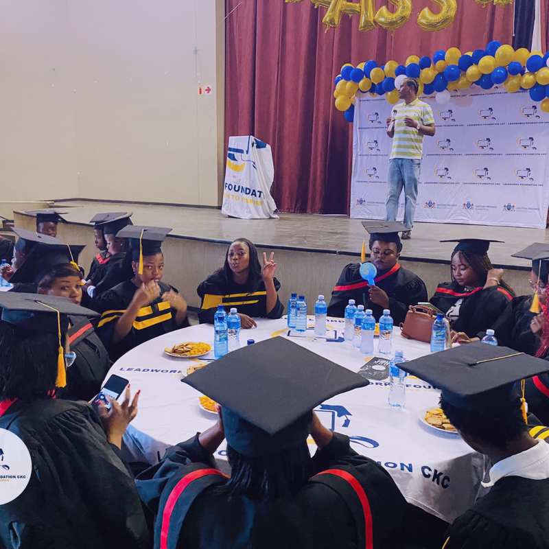 Leadworks Foundation graduates celebrate at a graduation ceremony while a speaker addresses the audience on stage.